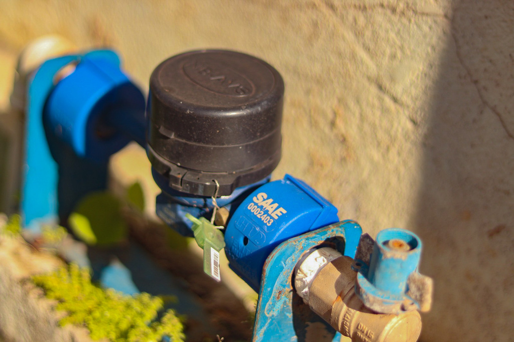 A foto mostra um hidrante com a tampa preta e um lacre azul onde se lê: SAAE.