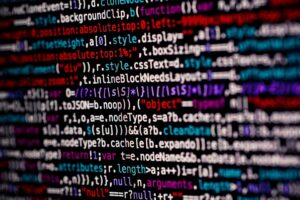 reprodução parcial de uma tela de computador, com símbolos e códigos de programação com letras em várias cores