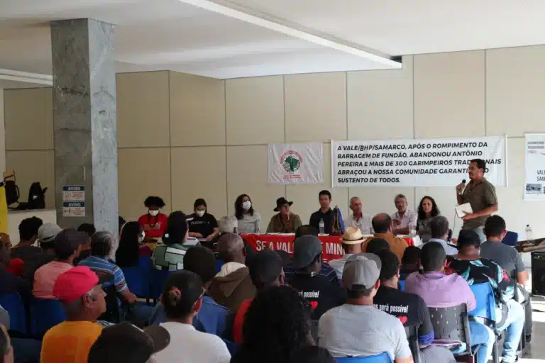 Depoimento de um representante dos garimpeiros, posicionado à direita, na extremidade da mesa que conduziu os trabalhos da audiência pública, convocada para debater o fechamento de garimpos pela polícia federal. Em primeiro plano, pessoas assentadas, participam da reunião