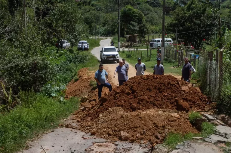 Equipe técnica, com seis homens, analisa situação de estrada, tendo à frente um monte de terra, para estabelecer a forma de executar obras no Salto (distrito de Ouro Preto) e conseguir liberação do trânsito na via. Ao fundo, alguns veículos estacionados