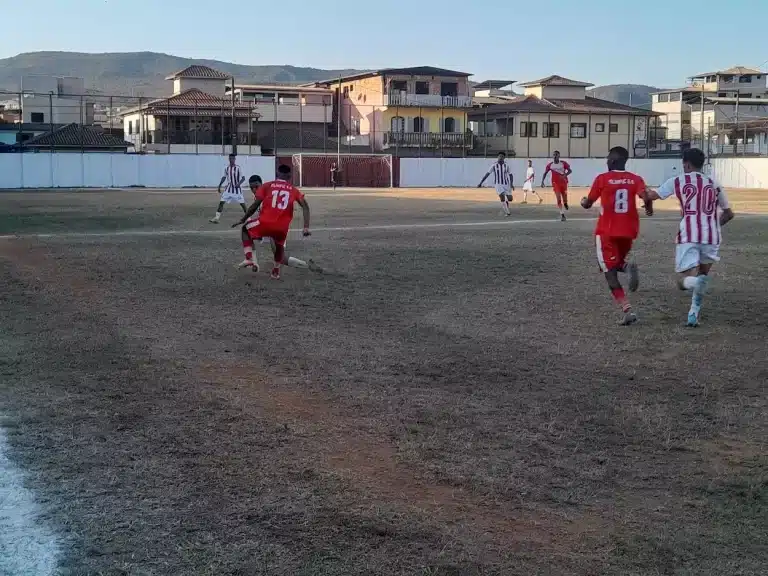 Jogadores do Olimpic (camisas e calções vermelhos) e Guarani de Furquim (camisas com listras verticais brancas e vermelhas, calções branos), disputam partida decisiva de classificação à semifinal dos juniores