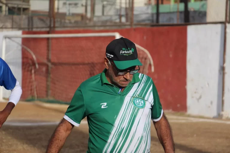 Usando boné e camisa verde, com listras diagonais brancas, Toninho Rocha, depois de invadir o gramado, na partida contra o Olimpic, pelo Campeonato de Mariana