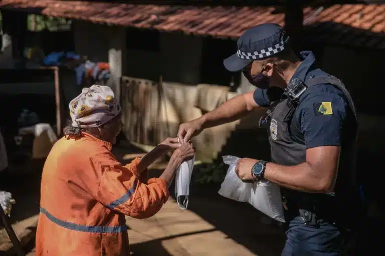 Integrante da Guarda Municipal instrui idosa sobre o uso de máscara como proteção contra o coronavírus