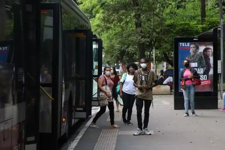 Pessoas desenbarcam de ônibus, respeitando a recomendação do uso de máscaras contra a Covid-19