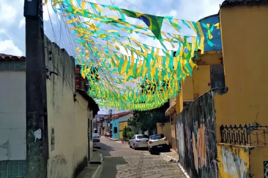 Bandeiras e fitas em verde amarelo, enfeitam uma rua, em alusão à Copa do Mundo, ilustrando a crônica Fim de Jogo