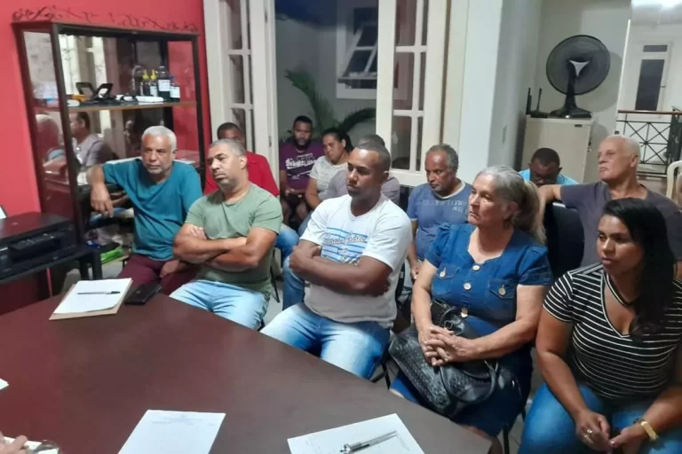 Grupo de pessoas sentadas ao redor de uma mesa, em reunião da FEAMMA (Federação das Associações de Moradores de Mariana)