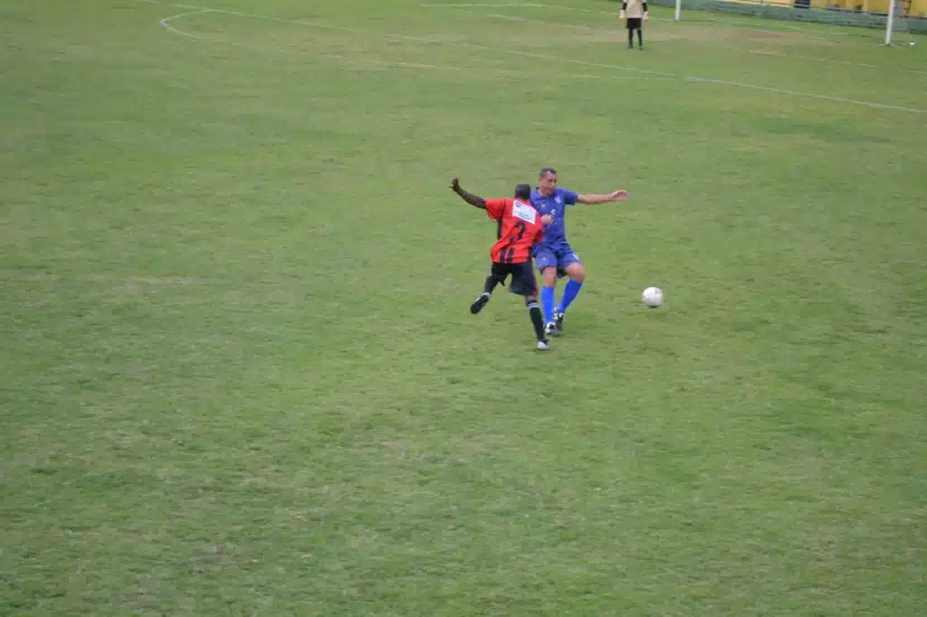 Jogador do 13 de Maio (uniforme vermelho e preto) disputa jogada contra atleta do Aluminas (uniforme azul), e se recupera da derrota sofrida na estreia