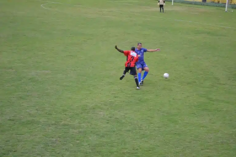 Jogador do 13 de Maio (uniforme vermelho e preto) disputa jogada contra atleta do Aluminas (uniforme azul), e se recupera da derrota sofrida na estreia